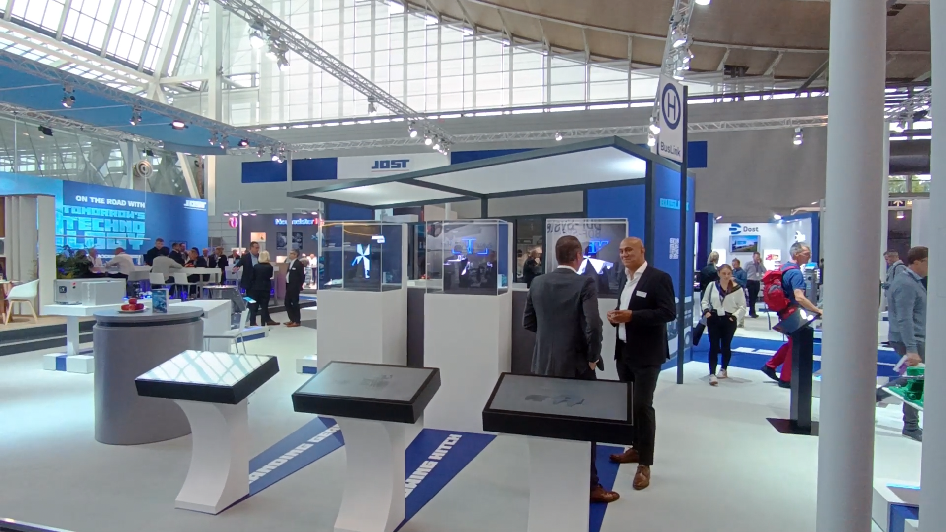 Interaktiver Messestand auf der Messe, Besucher unterhalten sich, viel Betrieb, Anwendung wird aktiv genutzt